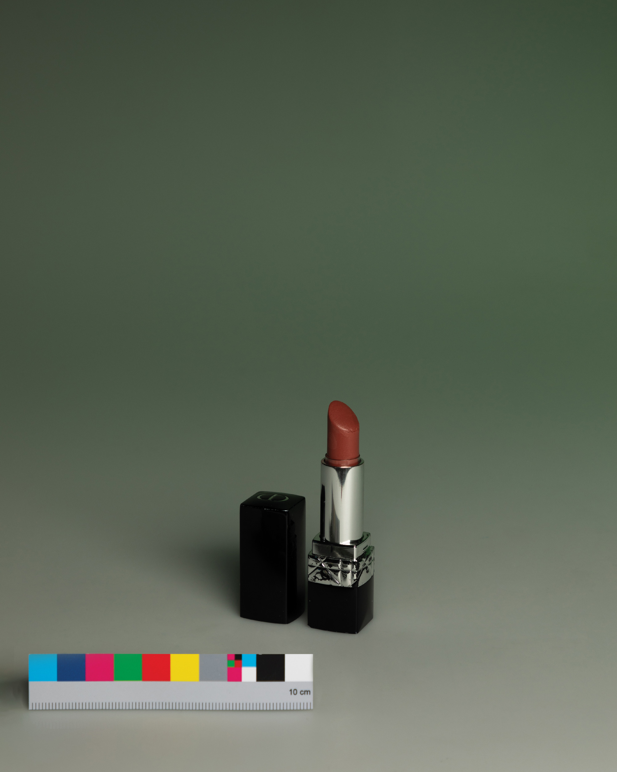 Catalogue photograph of a red lipstick on green with a colour chart, collection of Holly van Houten